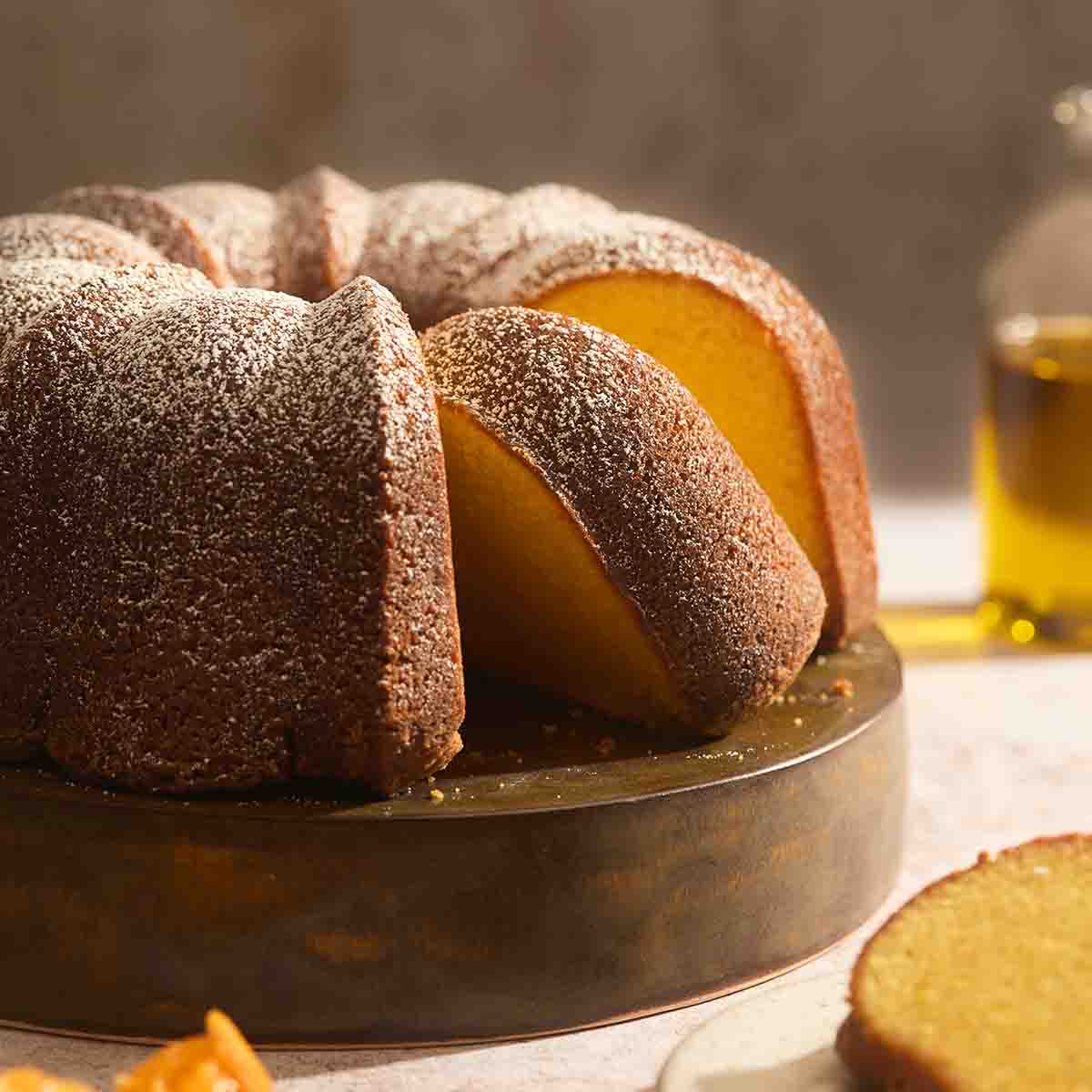 Close up shot of a moist orange olive oil cake slice showing a tender crumb and golden crust.