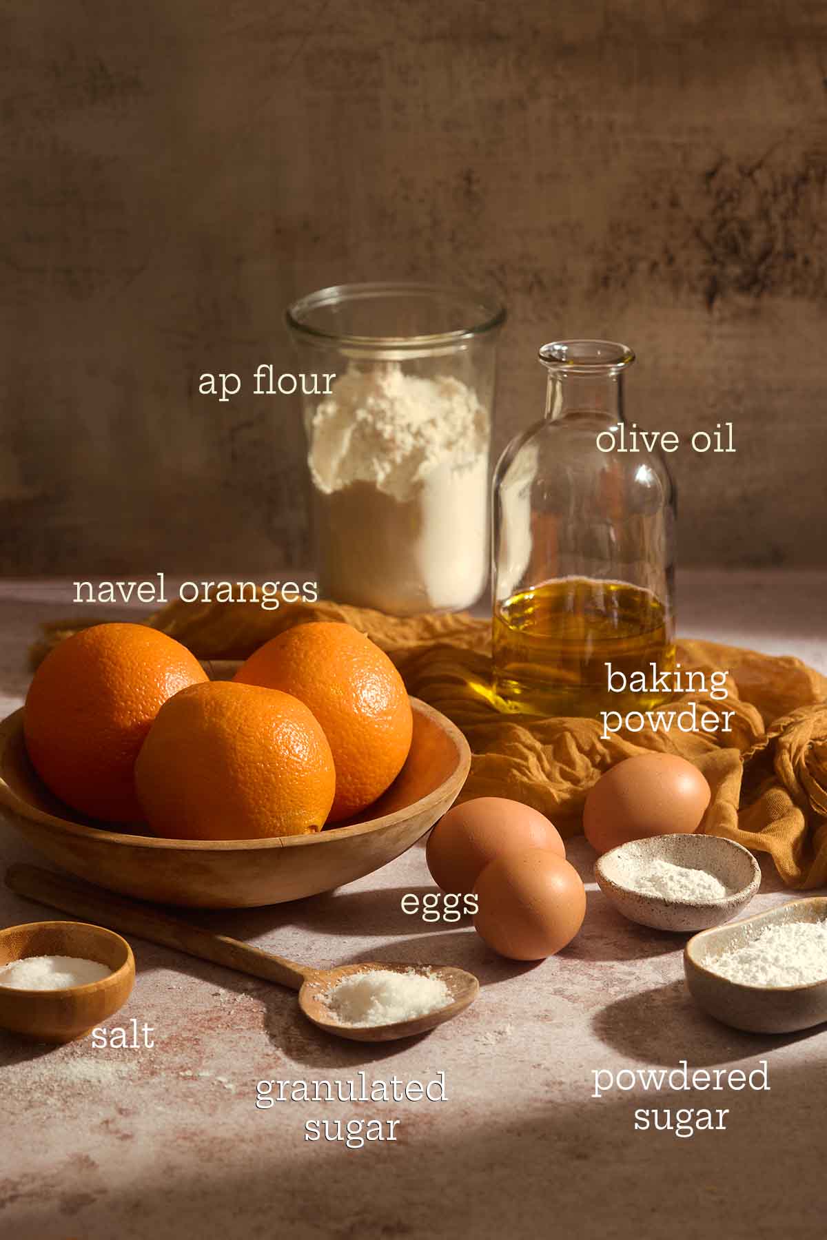 Raw ingredients for orange olive oil cake including flour, eggs, olive oil, and fresh navel oranges.