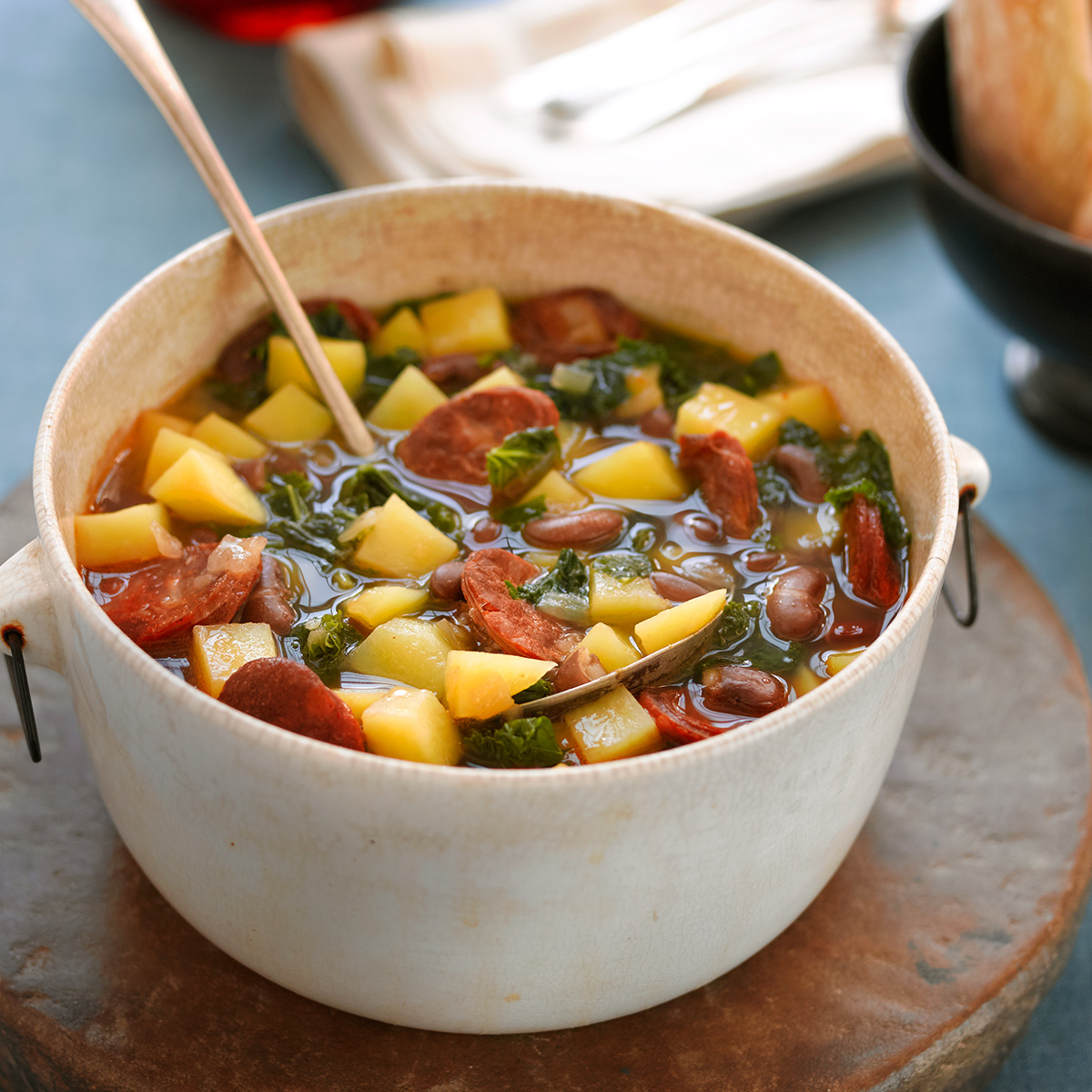 A antique white soup kettle filled with a Azorean kale and bean soup.