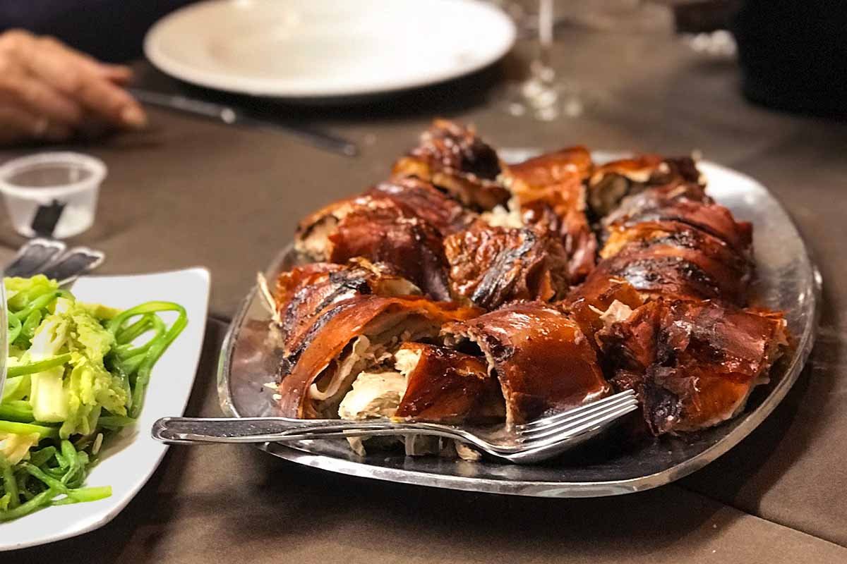 A platter of Portuguese roast suckling pig on a table.