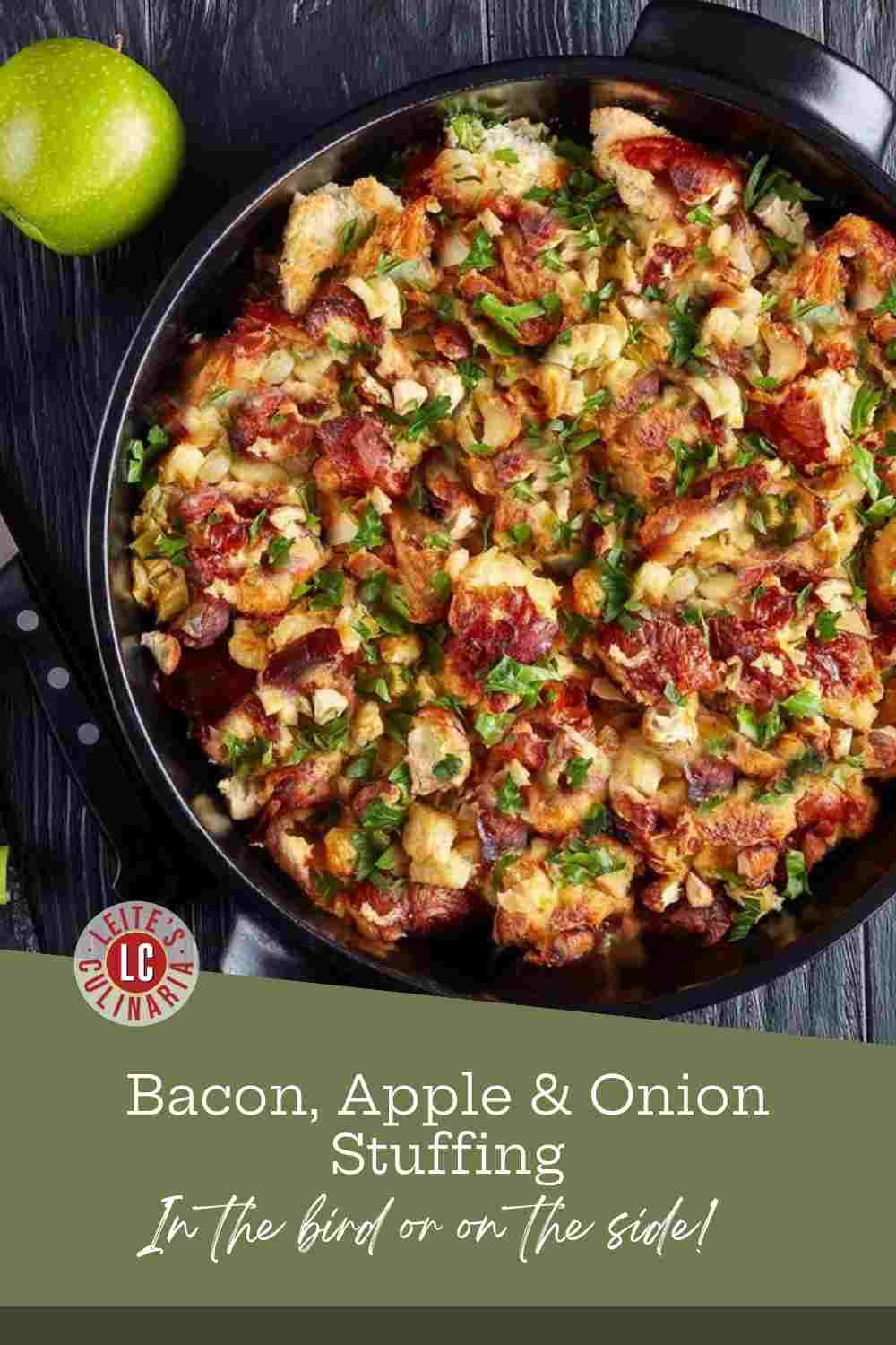 Bread stuffing with bacon, apples, and fresh sage filling a black skillet, a green apple at the edge.