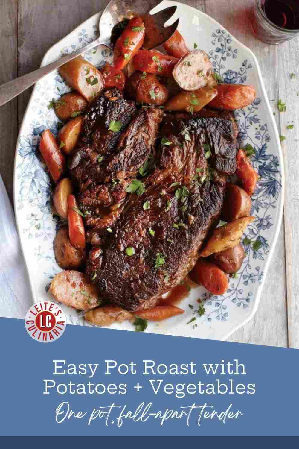Sliced pot roast with carrots and small potatoes on a blue-and-white floral platter, parsley scattered over.