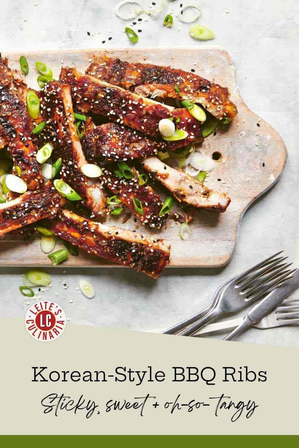 Dark-glazed pork ribs piled on a pale wooden board, scattered with scallions and black and white sesame seeds.