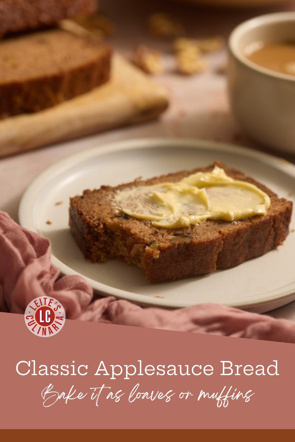 A buttered slice of applesauce bread on a cream plate beside a mug of coffee, with more slices on a board behind.