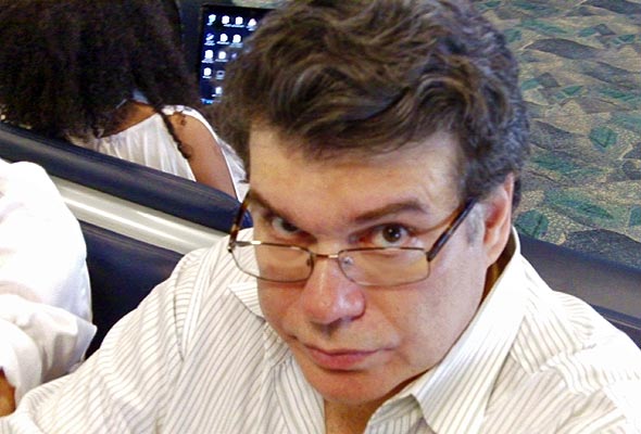 Photo of David wearing a white shirt and glasses looking at the camera with an attitude.