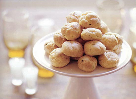 Cheddar-chive gougeres on a cake stand with glasses in the background.
