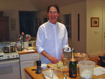 Deborah in a white shirt, in her kitchen with box grater on counter in front of her.