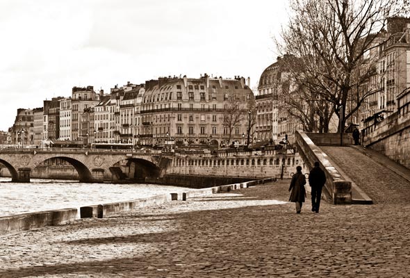 Two people walking along the Seine in Paris.