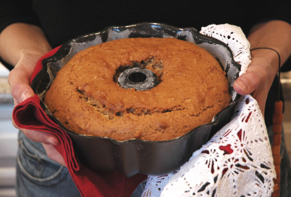 A photograph of a phanouropita cake being held in a bundt pan with a lacy dishcloth.