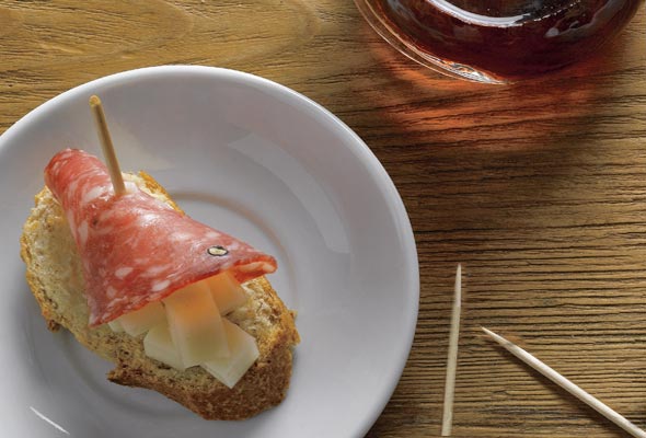 Salami-cheese tapa on a plate, held together with a toothpick.