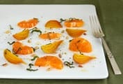 Tangerine and beet salad on a white plate, garnished with basil.